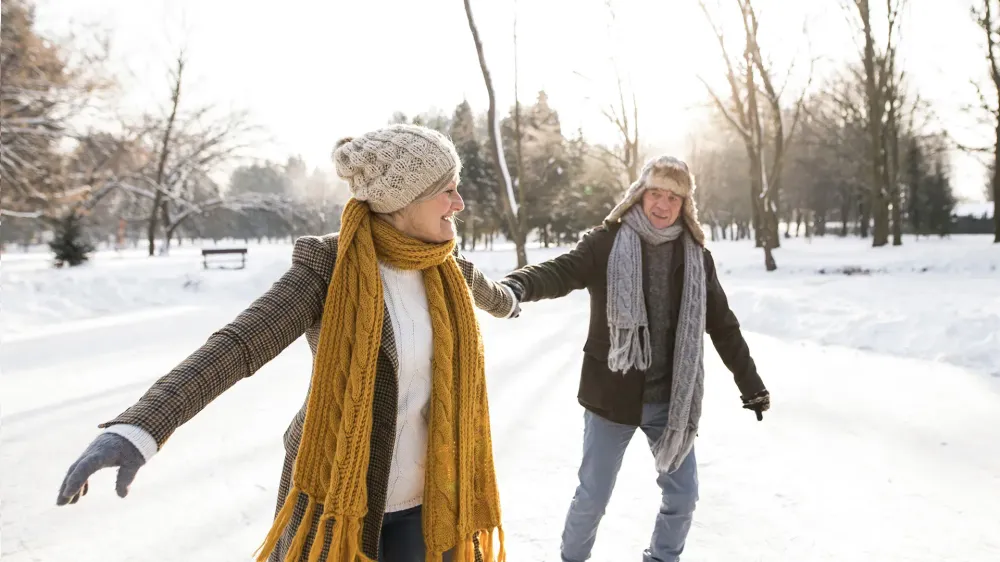senior couple ice skating wearing winter gear